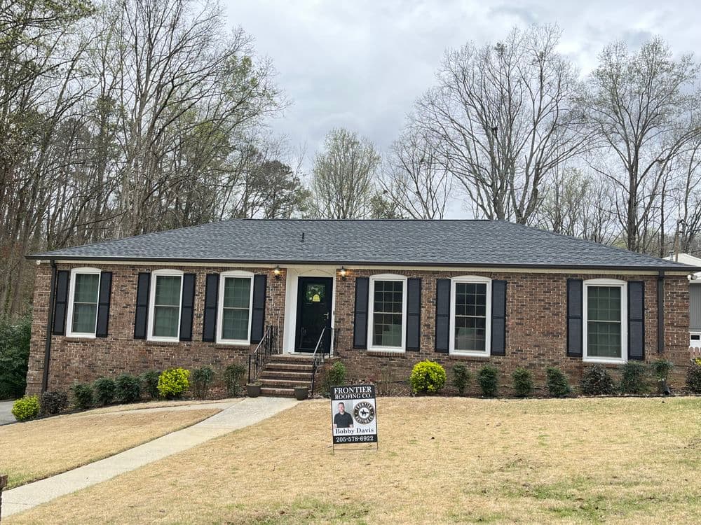 Brick home with black shutters, well-maintained lawn, and "For Sale" sign in front.