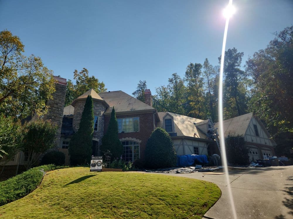 Home exterior with pitched roofs, manicured lawns, and trees in the background on a sunny day.