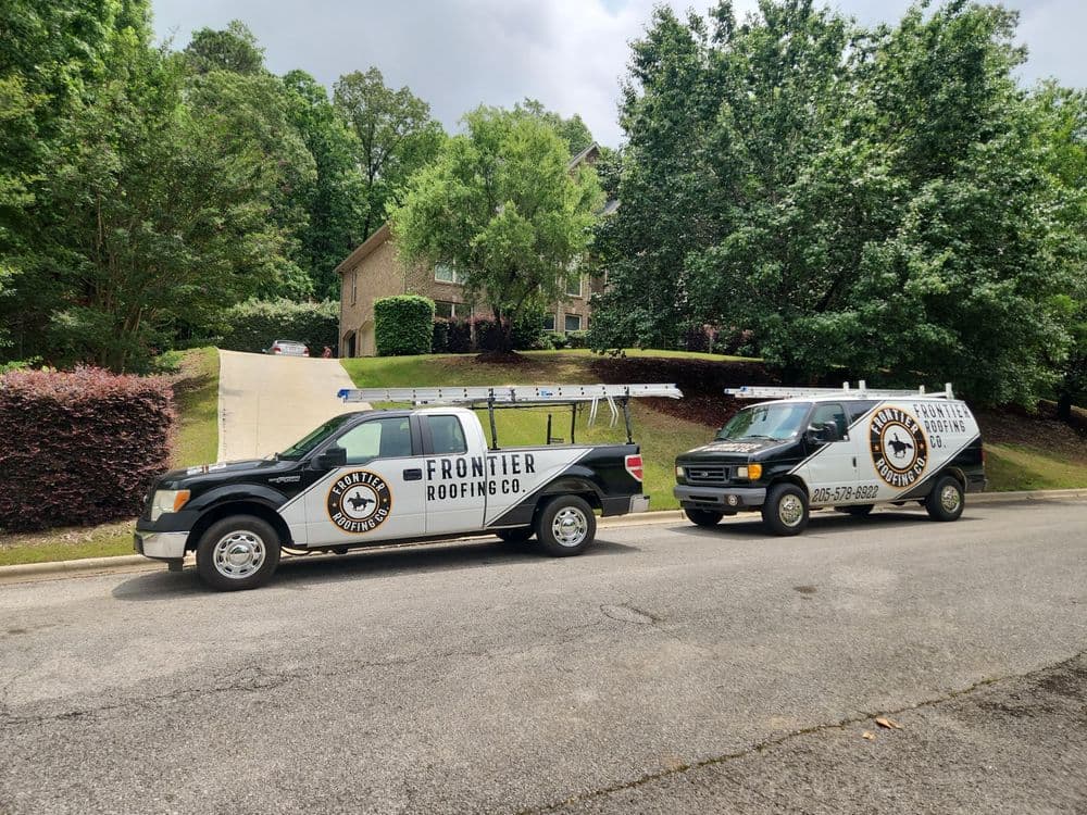 Frontier Roofing trucks parked outside a residential home with green landscaping.