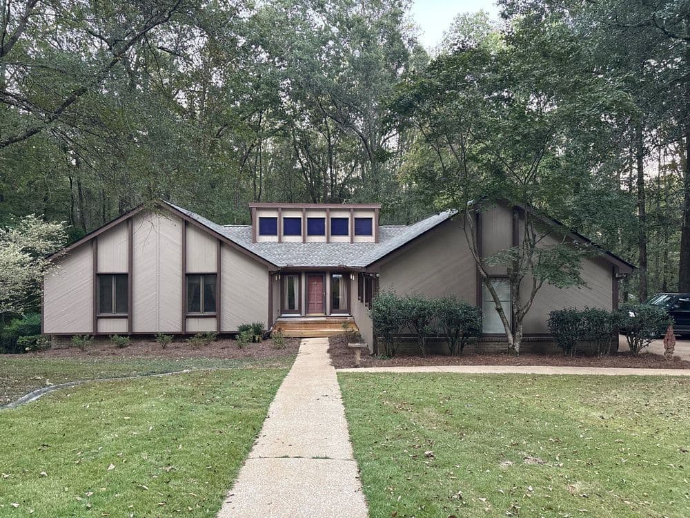 Modern single-story home surrounded by tall trees and landscaped yard, featuring a welcoming entrance.