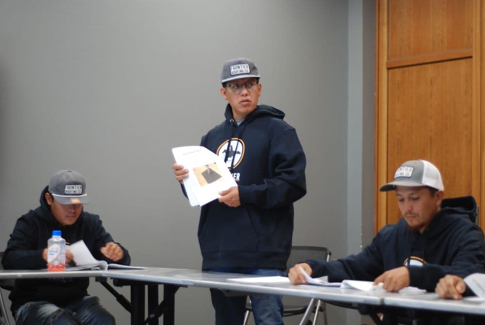 Worker presenting documents to team in a meeting, showcasing collaboration and discussion.